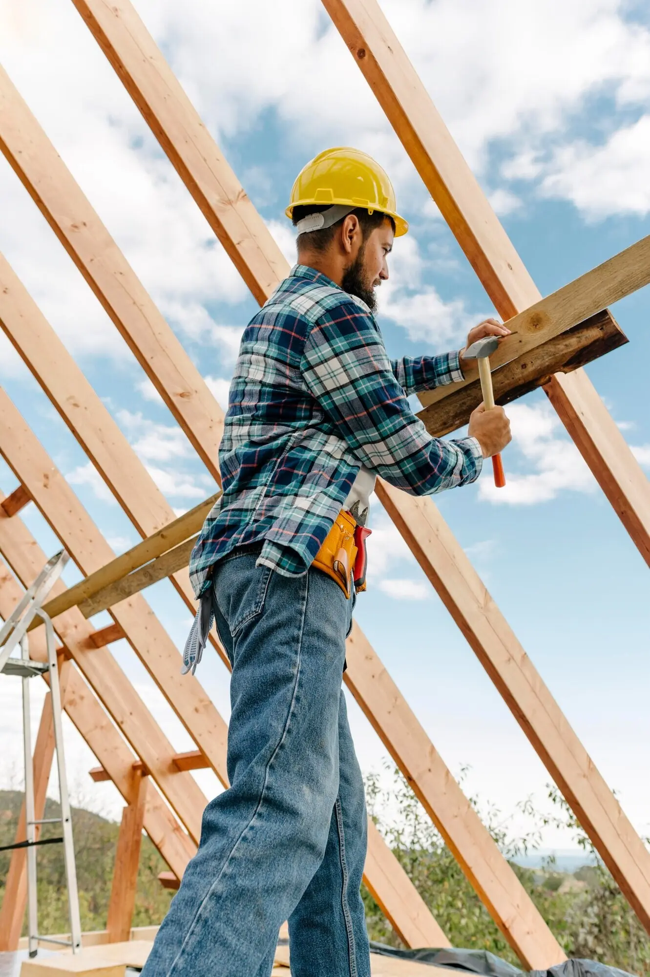 A hard-hat-wearing construction worker building the house’s roof.